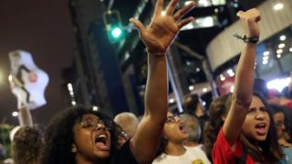 Meninas com os braços levantados e gritando em protesto em rua de São Paulo