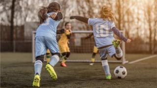 Молодые девушки играют в футбол