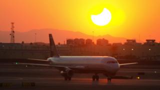 Plane taxis at Phoenix airport in front of sunset