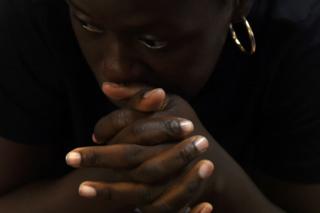 A woman clasps her hands together as she sits at a Greyhound bus station in San Antonio, Texas, on 11 June.