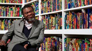 Yinka Shonibare poses with his art piece called The British Library at Tate Modern in London, UK - Monday 8 April 2019