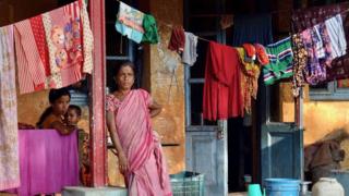 A woman stands outside a shelter in Silchar