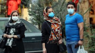 People wearing face masks stand on a street in Tehran, Iran (6 October 2020)