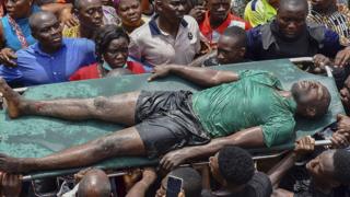Rescue workers carry a man rescued from the ruble at the scene of a building collapse in Ita Faji, Lagos, Nigeria, 13 March 2019