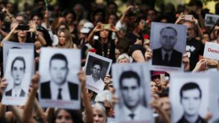 Pessoas seguram fotos de vítimas da ditadura militar em protesto contra a comemoração dos 55 do golpe militar, em SP