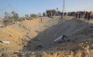 Palestinians gather around a crater after an Israeli air strike at Deir al-Balah, in Gaza