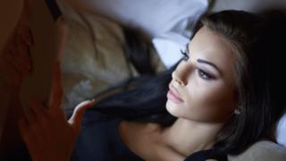 A woman reading a tablet in bed