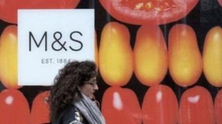 Woman walks by M&S storefront