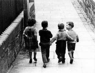 Four children walking down a street, 1966.