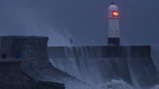 The teenagers can be seen trying to avoid the waves at they hit the breakwater
