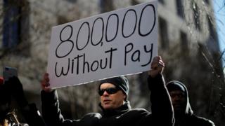 A protester holds a sign signifying hundreds of thousands of federal employees who won't receive salaries as a result of the partial government shutdown. Washington Jan 10 2019