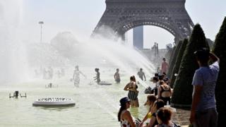 Gente bañándose en las fuentes frente a la Torre Eiffel.