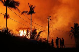 Lava erupts from a Kilauea volcano fissure as people gather on a residential street in Leilani Gardens, on Hawaii"s Big Island, on May 23, 2018 in Pahoa, Hawaii