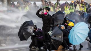 Pro-democracy protesters react as police fire water cannons outside the government headquarters in Hong Kong on 15 September 2019