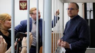 Former US Marine Paul Whelan stands inside a defendants' cage as he attends a court hearing regarding the extension of his detention