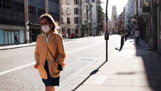 A masked woman walks the deserted streets of London