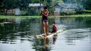 बाढ़ के पानी पर नाव चलाते बच्चे