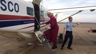 Justin Welby embarks on an aircraft in Uganda