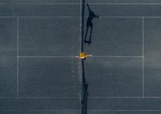 Petra Leary is an award winning New Zealand born aerial photographer. Petra has been up high well before drones and has worked at her aerial photography style for many years. This photo shows a skateboarder jumping over a net on a concrete tennis court