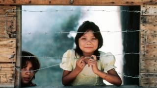 Niña en América Latina detrás de un línea de alambre de púas