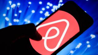 Смартфон с логотипом сервиса Airbnb на экране.