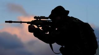 The silhouette of a soldier aiming a gun