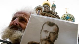 Un hombre con un retrato de Nicolás II