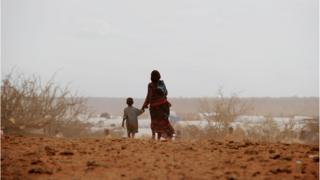 Woman and little boy walking on a dry land.