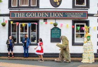 People in costume entertain pub customers on the street
