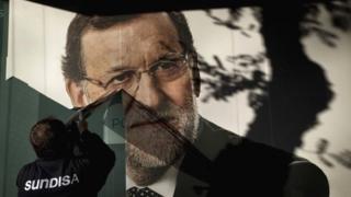 A worker removes a campaign poster for the national elections, Madrid 21 Dec