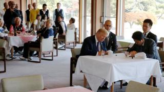 特朗普(前左)与安倍晋三(前右)在埼玉县霞关乡村俱乐部餐厅内于鸭舌帽上签名(5/11/2017)
