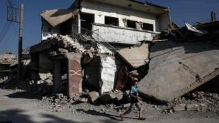 A boy walks past destroyed buildings in the rebel-held town of Douma, on the eastern outskirts of Damascus. Photo: 6 May 2017