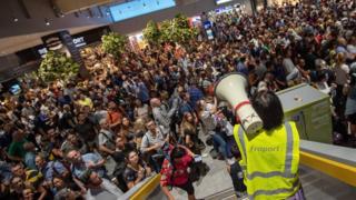 Fraport staff informs passengers and visitors who are waiting for the evacuation to end at Frankfurt Rhein Main Airport