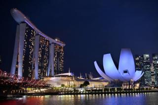 The Marina Bay Sands hotel and resorts (L) and the ArtScience Museum (R) are illuminated under the evening sky in Singapore on March 8, 2019