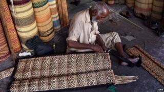 A man makes curtains to offer protection from heat in Karachi