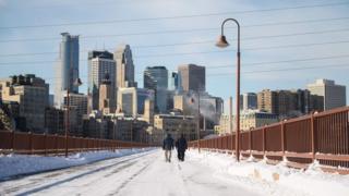 A couple walk through city street amid snow