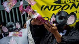 Seorang pengunjuk rasa mengenakan topeng tikus perlambang koruptor