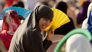 Abandi bagore b'abayisilamukazi muri Esipanye baturuka mu majyaruguru ya Afurika bifashishije utuntu tubahungiza kubera ubushyuhe nyuma y'amasengesho mu gace ka Cueta nyuma y'amasengesho ya Eid al-Fitr.