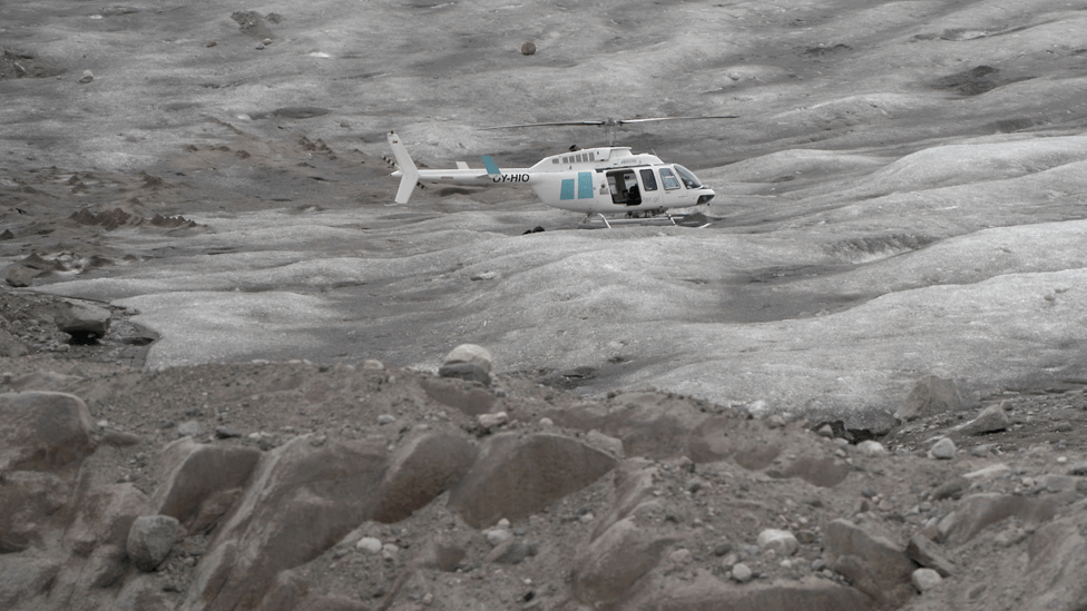 Helicopter flies over Sermilik glacier