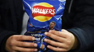 A boy holds a Walkers crisp packet in his hands