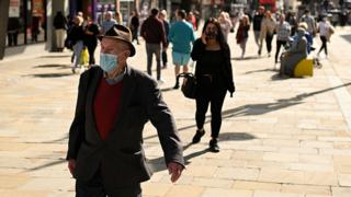 Pedestrians and shoppers, some wearing a face mask or covering walk past shops in Newcastle city centre, north-east England, on 17 September