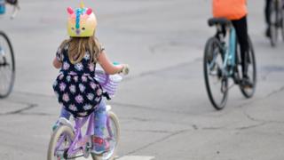 Child cycling behind an adult