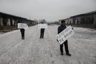 Migrants hold placards during a protest outside a derelict customs warehouse in Belgrade, Serbia