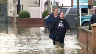 People walk in floodwater next to homes in Gloucester on 4 January