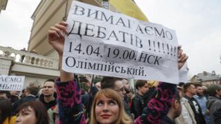 Активістка з плакатом "Вимагаємо дебатів"