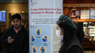 A woman walking past a Public Health England sign