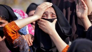 Плачущие женщины с закрытыми головами скорбят во время похоронного шествия подозреваемого боевика