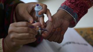 An election official marks a voters thumb before casting her vote
