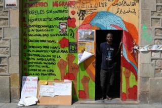 Ugandan Francis Kashamba poses at the frontdoor of the abandoned school of La Massana, in the center of Barcelona, on July 3, 2018, occupied since mid-April by dozens of migrants. Once far from the strife that pushed them to come to Europe, what has awaited thousands of illegal migrants in Spain is a form of agonising purgatory, according to the migrants occupying the Massana School