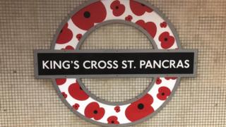 A London Underground roundel is modified with poppies, at King"s Cross St Pancras station